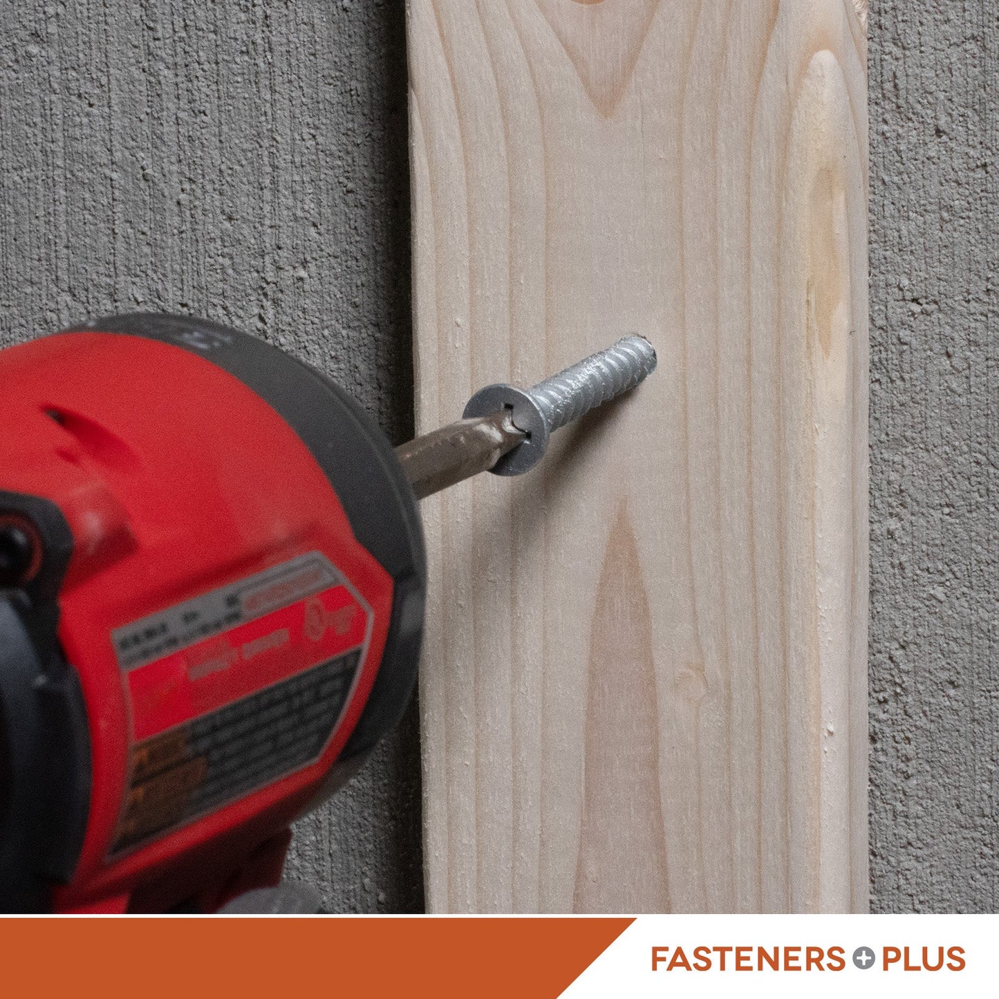 Red drill driving a concrete screw into a wooden board with 'Fasteners Plus' branding.