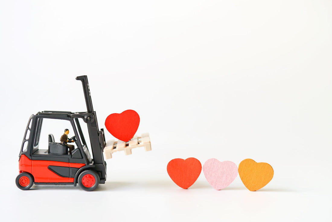 miniature forklift hoisting up red heard on a small pallet