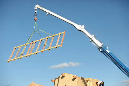 image of crane with a quad-leg lifting sling moving a wooden frame onto a building site