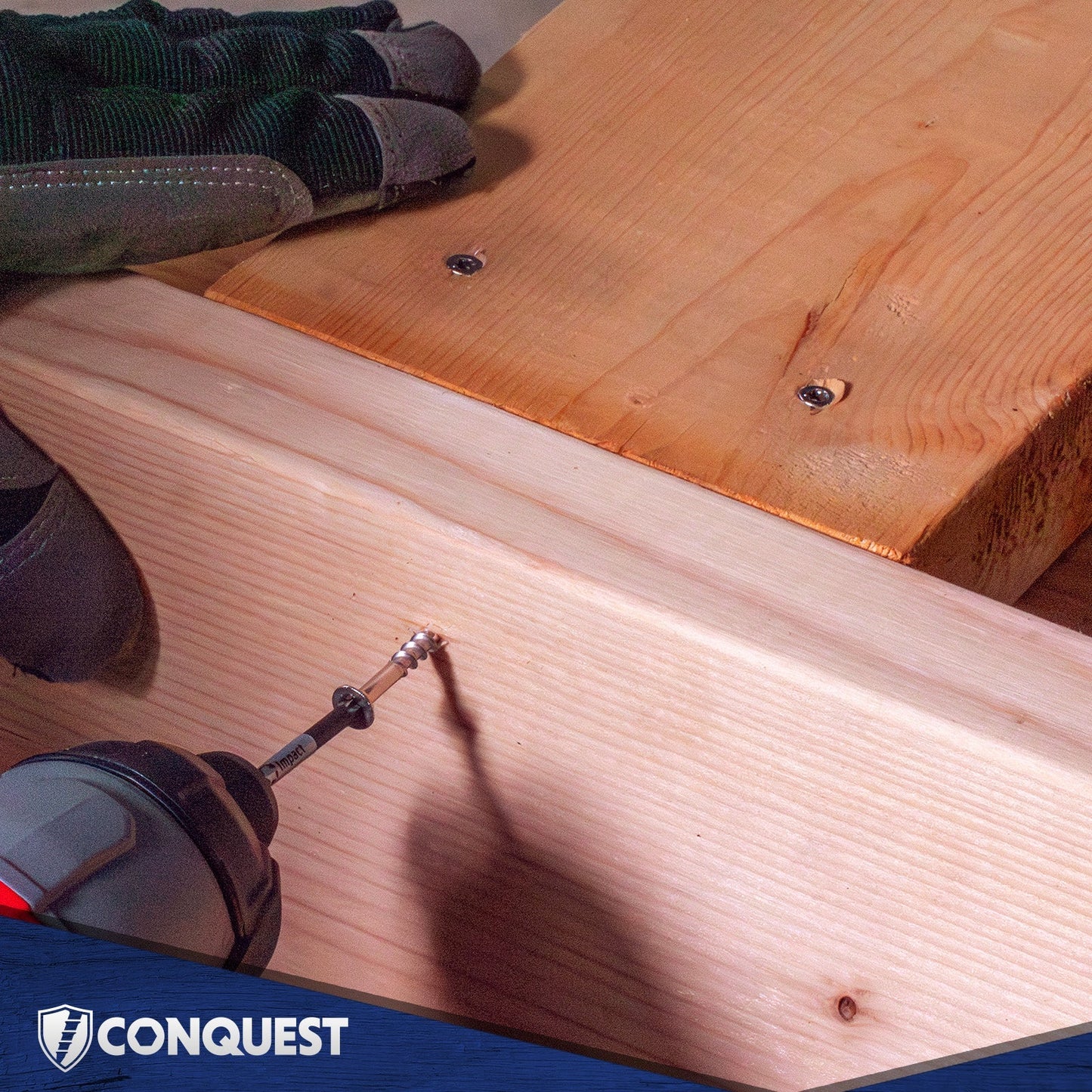 Wooden surface with a drill and a hand wearing a glove, branded 'Conquest'.