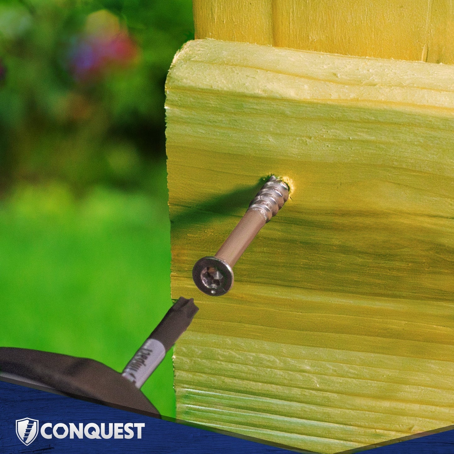 Screw being driven into a yellow wooden surface with 'Conquest' branding visible.